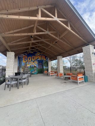 A stylish covered pavilion in Village on Cooper Lane by David Weekley Homes in Austin, TX, featuring modern seating, dining areas, and a vibrant mural.