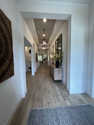 Model Home A bright hallway featuring wood floors, modern lighting fixtures, and a stylish side table with decor accents.