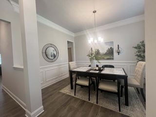 A chic dining room with elegant wainscoting, modern chandelier, and a stylish table setup.