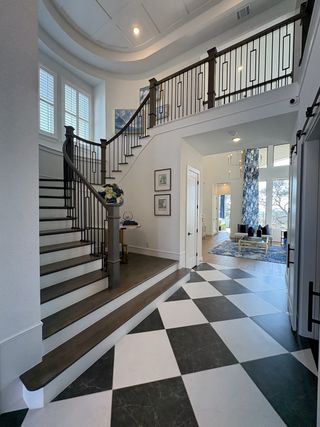 A grand foyer with a sweeping staircase, geometric tile flooring, and elegant decor.