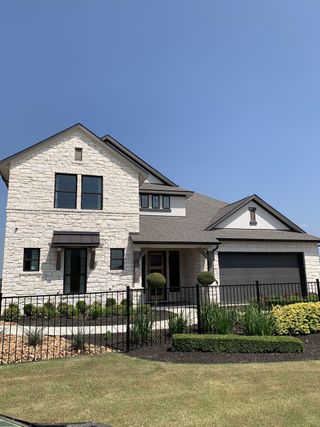 Street view A beautiful stone facade home with manicured landscaping in Enclave at Cele by GFO Home (Pflugerville, TX).