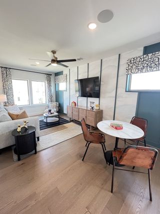 A modern living area with a cozy sofa, sleek TV setup, round dining table, and stylish decor accents.