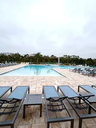 A pristine pool with lounge chairs and a fountain, perfect for relaxation in Toscana Village at Verona by KB Home (Titusville, FL).