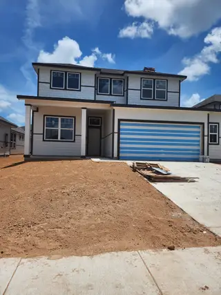 Street view A modern two-story home with a striped garage in Paramount by Chesmar Homes (Kyle, TX).