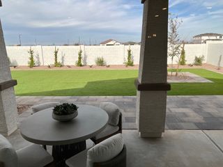 A lovely backyard patio with a round table, cushioned chairs, and a view of a landscaped yard and garden wall.