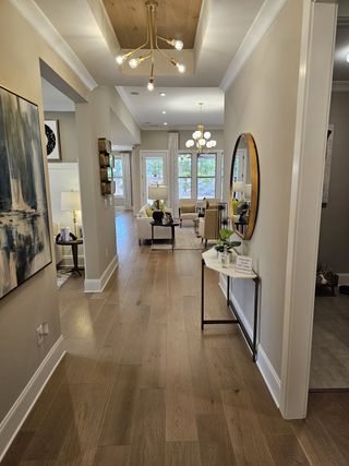 A stylish entryway with wood flooring, modern chandeliers, and elegant decor leading into a bright and inviting living area.