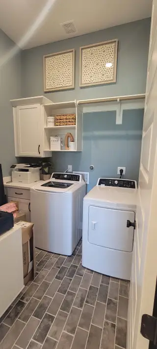 Model Home Efficient laundry room with white cabinetry, shelving, and modern appliances, designed for convenience