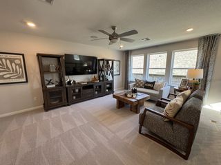 A cozy living room featuring neutral decor, plush seating, a wooden coffee table, and ample natural light through large windows.
