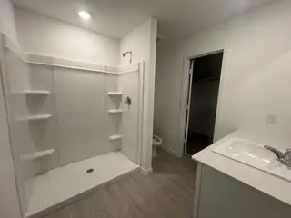 A modern bathroom with a spacious shower, sleek white vanity, and minimalist design.