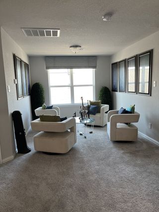 Model Home A cozy seating area with plush cream chairs, a glass table, and modern art, perfect for relaxing or conversation.