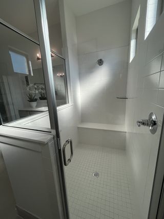 A spacious shower with sleek glass doors, crisp white tiles, and elegant fixtures.