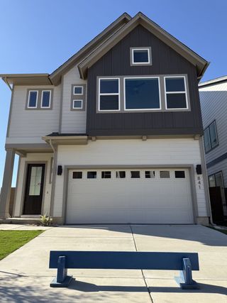 A modern gray and white home with large windows and a two-car garage in Double Creek Crossing by David Weekley Homes (Round Rock, TX).