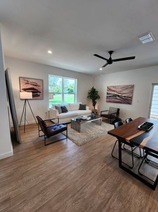 A modern living room with wood floors, sleek furniture, and large windows providing natural light.