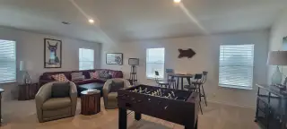 A versatile bonus room with neutral carpet, a foosball table, and comfortable seating offers a space for entertainment and relaxation.