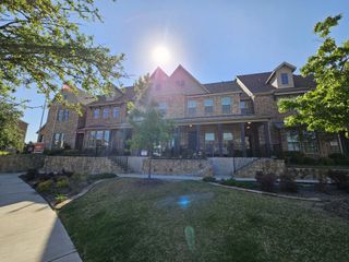 A charming brick townhome with lush greenery in Bayside by Beazer Homes (Rowlett, TX).
