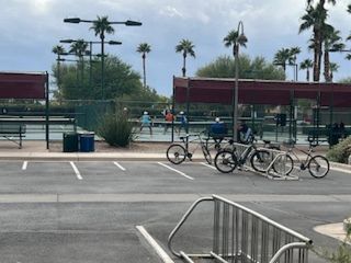 Tennis courts with palm trees and seating area at Robson Ranch Arizona by Robson Resort Communities (Eloy, AZ).