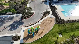 An aerial view of the Parkside On The River community, featuring the pool and playground for family fun (Georgetown, TX).