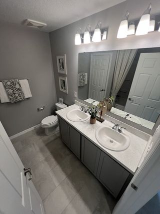 A modern bathroom with dual sinks, sleek light fixtures, and elegant decor in neutral tones.