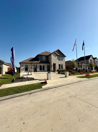 Street view A beautiful brick home with a spacious driveway in Sunterra by D.R. Horton (Katy, TX), showcasing modern suburban charm.