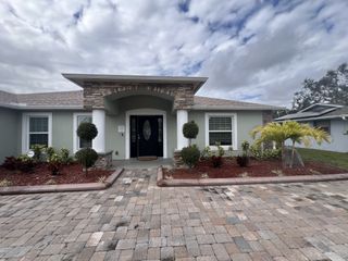 Street view A charming stone-accented home with manicured landscaping in Palm Bay & South Brevard by Avtec Homes (Palm Bay, FL).