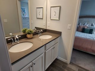 A modern bathroom with a sleek double sink vanity, chic decor, and a glimpse into a cozy bedroom.