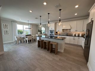 Model Home A spacious kitchen and dining area with modern lighting, a large island, and sleek cabinetry.