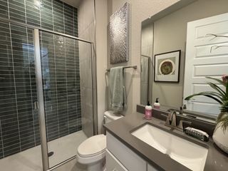 A modern bathroom with a sleek glass shower, elegant dark green tiles, and a chic vanity.