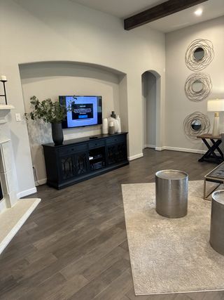 A cozy living room with wood flooring, modern decor, and stylish wall art. Dark media console complements the space.