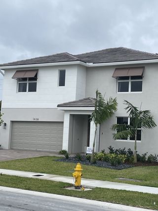 A modern two-story home with palm trees and a sleek design in Parker Pointe by D.R. Horton (Homestead, FL).