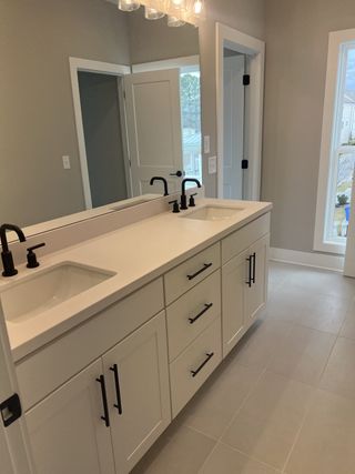 A modern bathroom with a sleek double vanity, black fixtures, and elegant lighting.