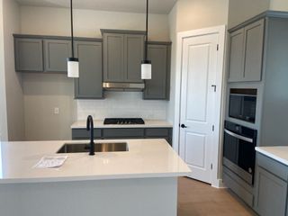 A modern kitchen with sleek gray cabinets, stainless steel appliances, and elegant pendant lighting.
