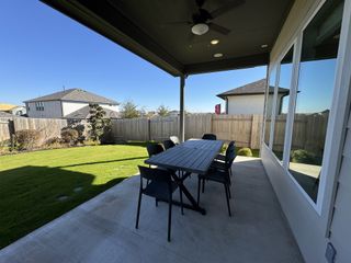 Model Home The backyard boasts a covered patio with an outdoor dining setup, perfect for entertaining.