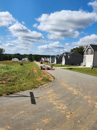 Street view A picturesque street view in Hawthorne West by Lennar, showcasing charming homes under a vibrant blue sky in Zebulon, NC.