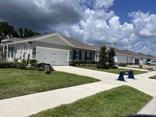 A modern ranch-style home with elegant stone accents and lush greenery in Park Ridge Villas by Ryan Homes (Spring Hill, FL).