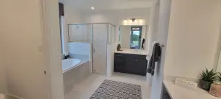 A spa-like bathroom with a walk-in shower, soaking tub, and dual vanity sinks accented by subway tile and dark cabinetry.