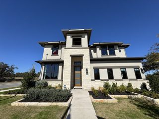 Street view A modern two-story home with elegant stone accents and lush landscaping in Retreat at San Gabriel by Brightland Homes (Georgetown, TX).