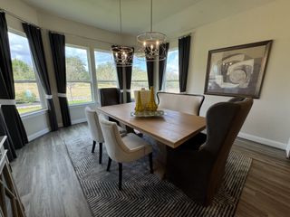 Model Home A stylish dining room with a wooden table, modern pendant lights, and large windows offering plenty of natural light.