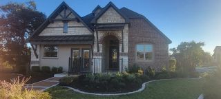 Street view Charming brick and stone home with a quaint garden in The Enclave at Potranco Oaks by Texas Homes (Castroville, TX).
