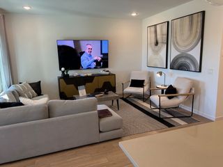 A modern living room with sleek furniture, stylish abstract art, and a cozy seating area. Neutral tones and contemporary decor.