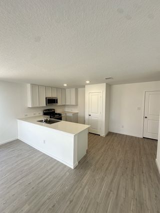 A modern kitchen with sleek white cabinetry, a spacious island, and wood-look flooring.