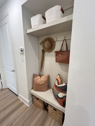 A stylish mudroom nook with cozy pillows, storage baskets, and elegant hooks on beadboard paneling.
