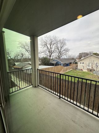 Street view A covered balcony with sleek railing and views of a fenced backyard and neighboring homes.