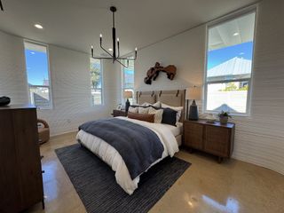 Model Home A cozy bedroom featuring modern lighting, textured walls, and a stylish wood accent above the bed.