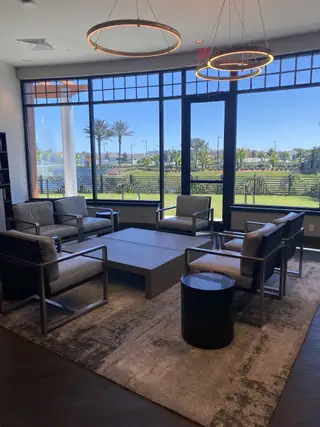 A stylish clubhouse lounge with contemporary seating, floor-to-ceiling windows, and scenic views of the lush community landscape in Del Webb eTown by Del Webb in Jacksonville, FL.