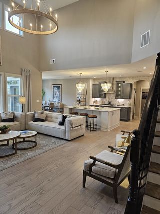 Model Home A grand two-story living room with a stunning chandelier, open-concept kitchen, and elegant neutral décor.