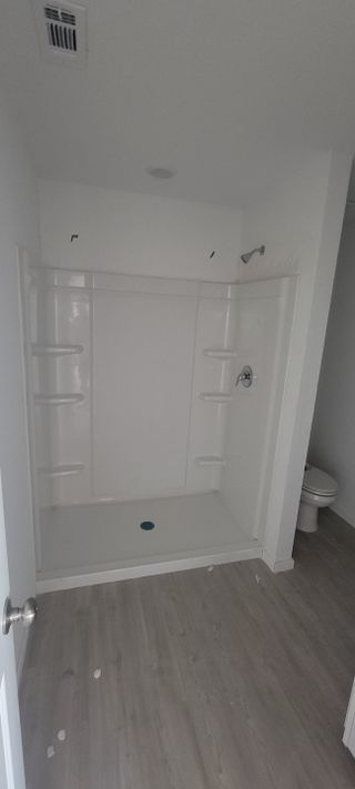 A modern bathroom with a sleek shower, light wood flooring, and minimalist design.