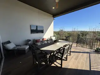 An inviting outdoor patio with a dining set, lounge area, and mounted TV, perfect for relaxing and entertaining.