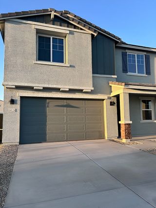 A contemporary home with a bold gray facade, green garage door, and charming shutters in North Copper Canyon by Century Communities (Surprise, AZ).