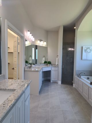 Elegant bathroom featuring granite countertops, a spacious shower, dual vanities, and soft, ambient lighting.