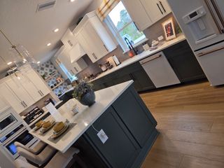 A contemporary kitchen with white upper cabinets, dark lower cabinets, and a chic tile backsplash.